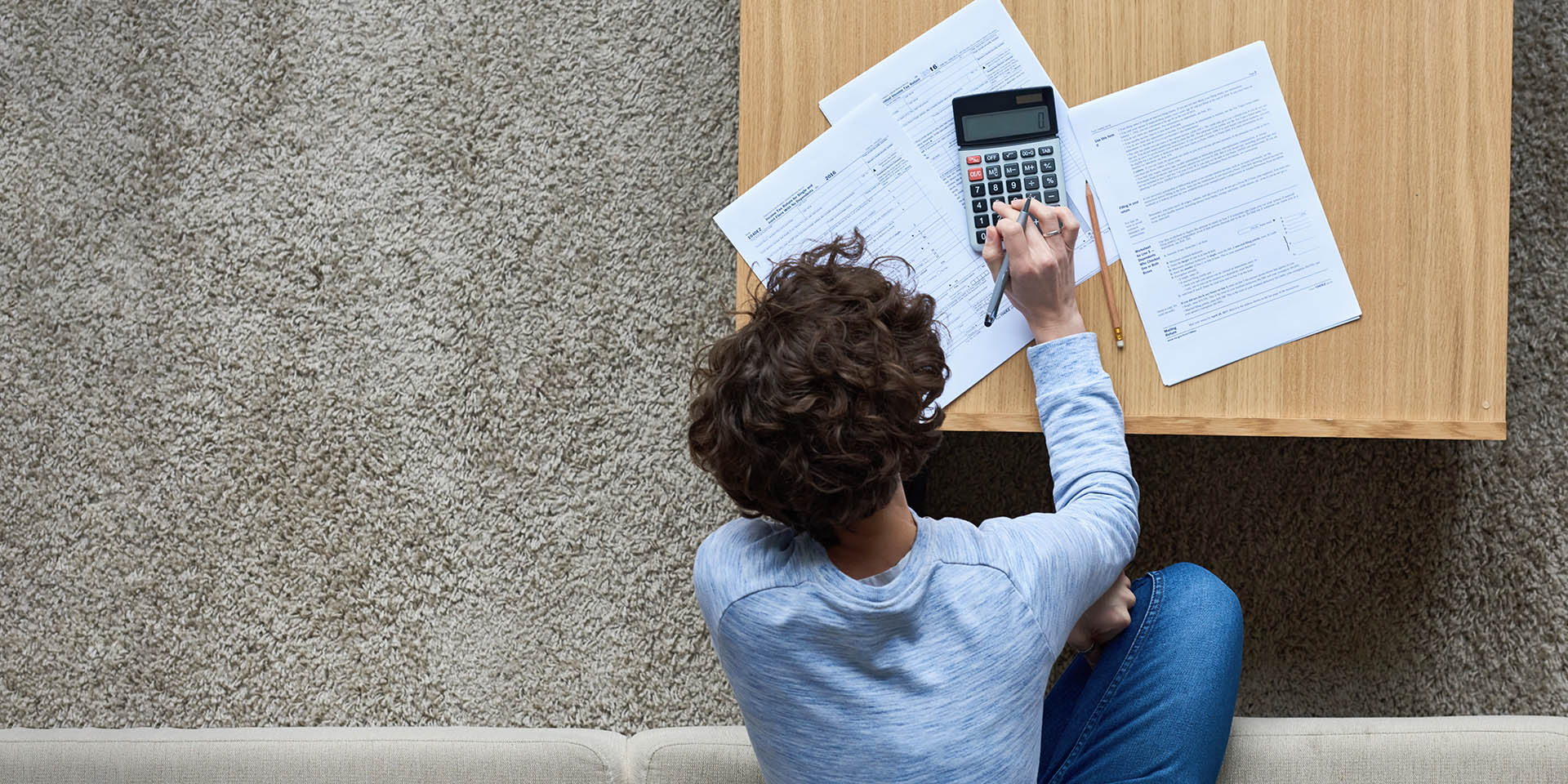 High angle view of curly woman calculating tax bill